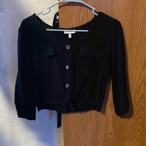 Black, cropped, long sleeve shirt w buttons in middle & pockets on both sides.